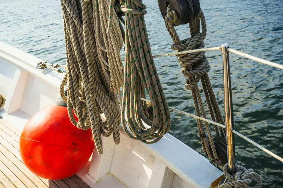 Coiled ropes and a red fender on the wooden deck of a boat