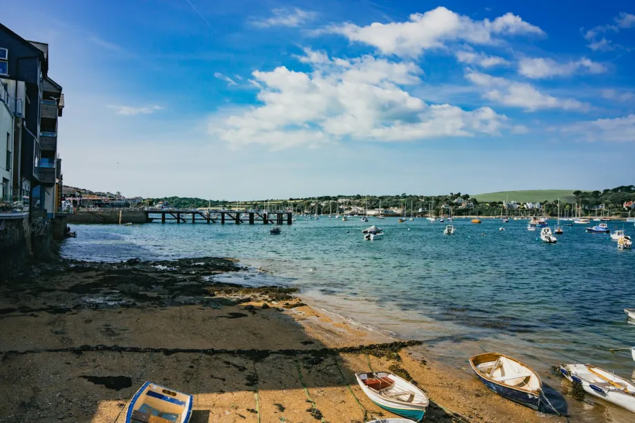 Small boats drawn up on a beach beside the water near Falmouth, Cornwall